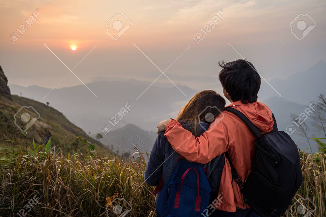 Loving couple embracing on the mountain at sunset.